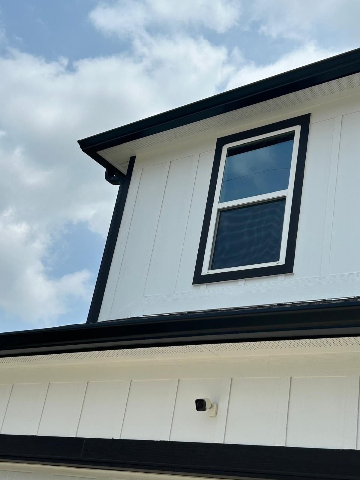 Black seamless gutter on white board-and-batten new construction — Houston TX