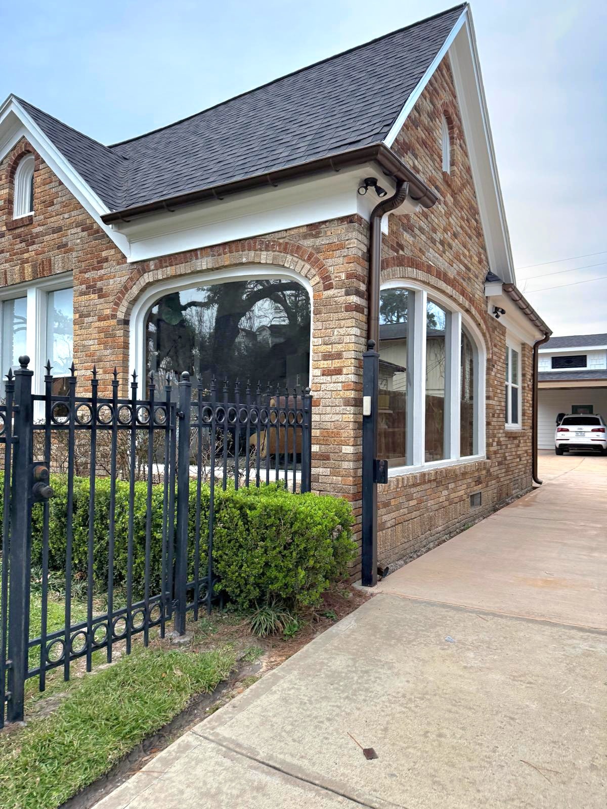 Gutter installation on brick home with iron gate and arched windows — Houston TX