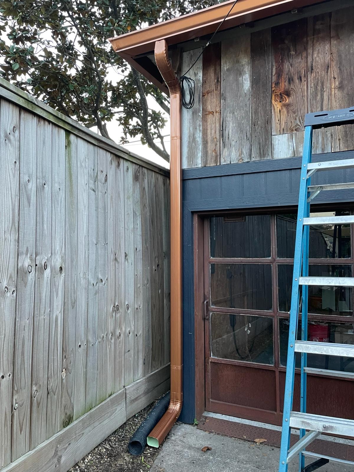 Copper downspout detail beside French door — Houston TX