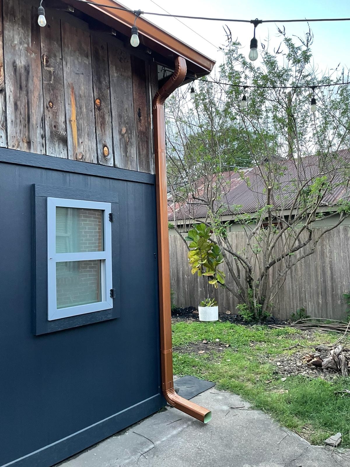 Copper downspout on navy board-and-batten siding — Houston TX