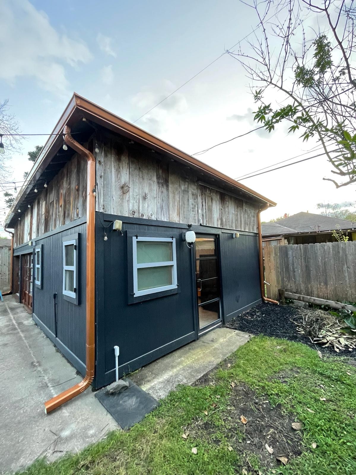 Copper seamless gutter installation on dark exterior building — Houston TX