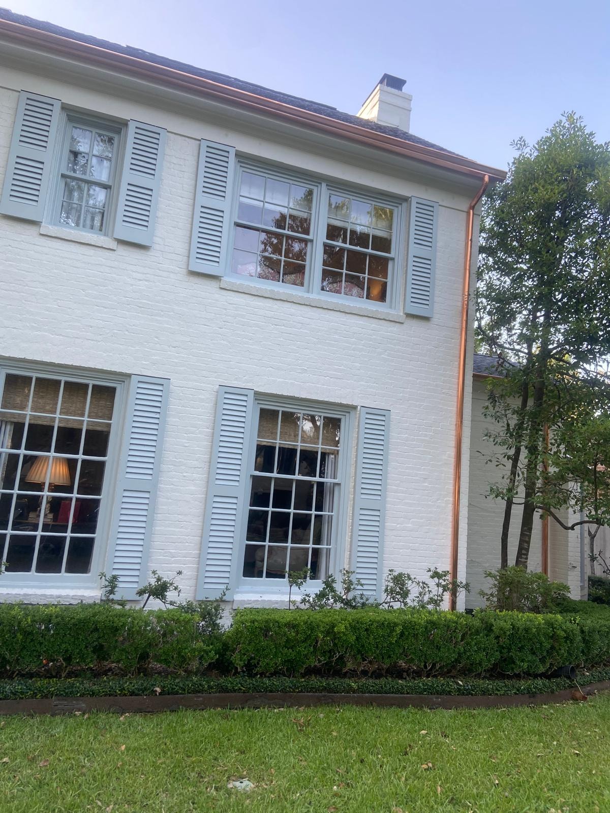 Copper gutter on white colonial brick home with blue shutters — Houston TX