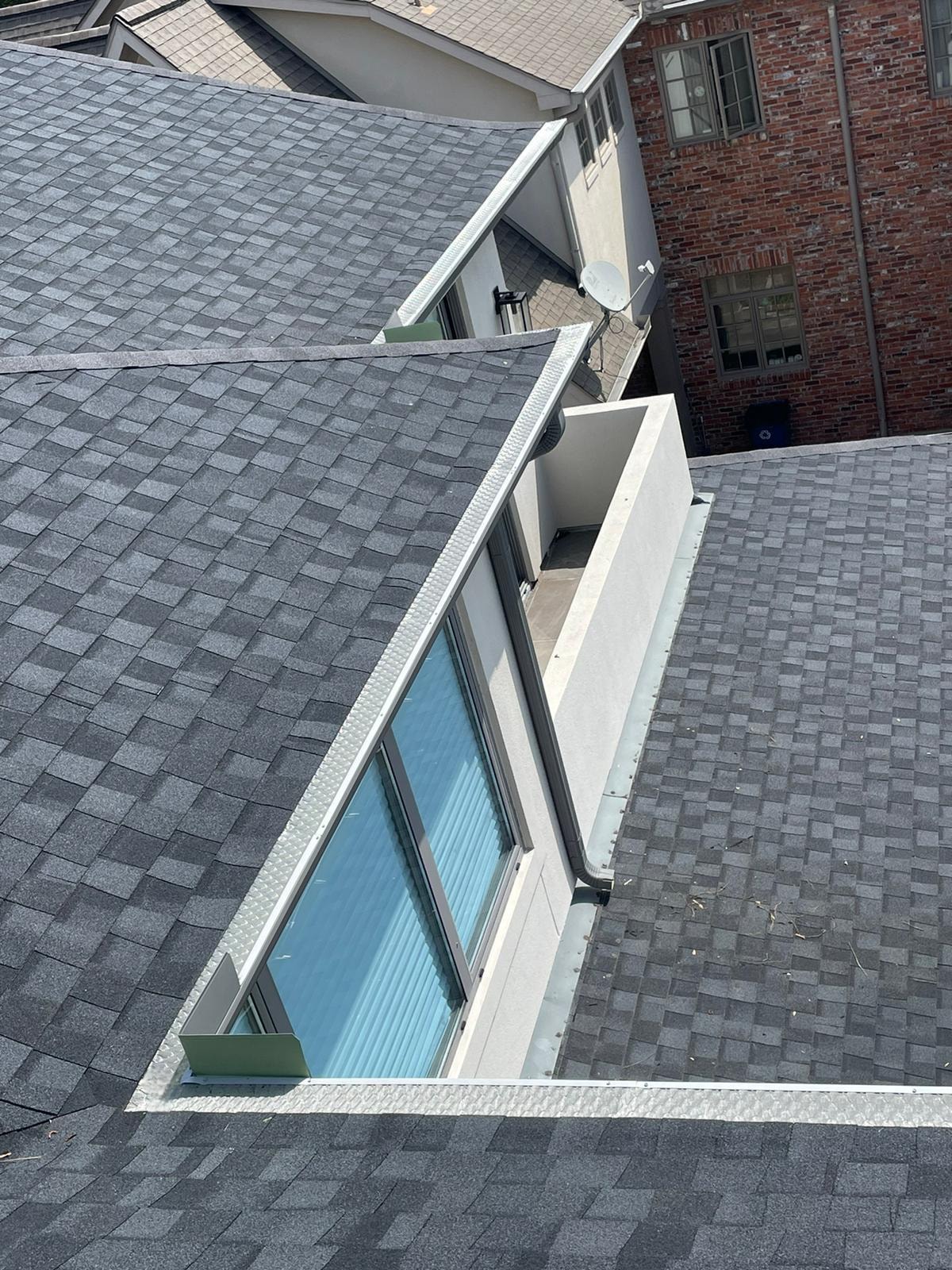 Aerial view of gutter guard installation along roofline with skylights — Houston TX