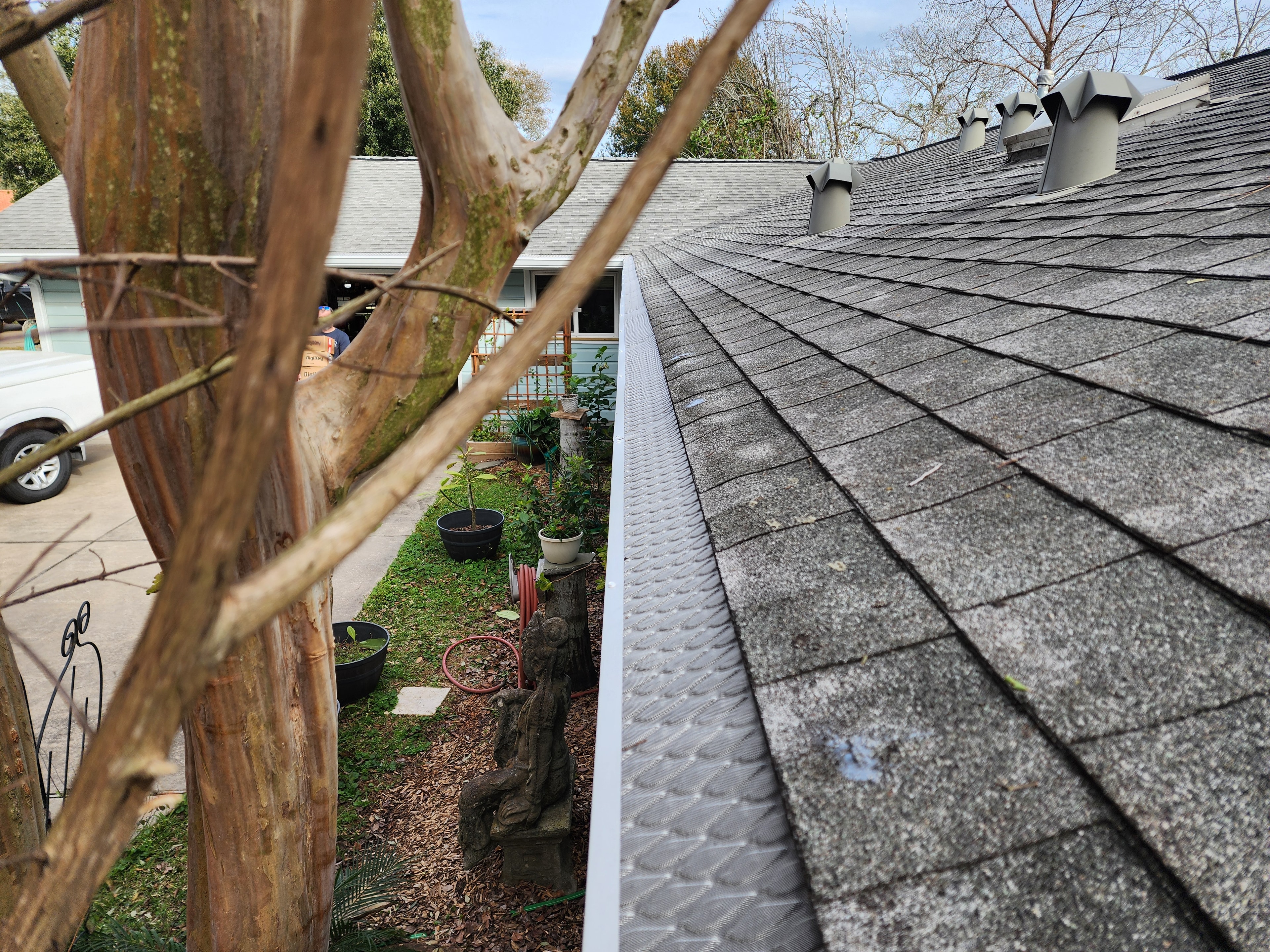 Gutter guard installed along roofline with mature trees