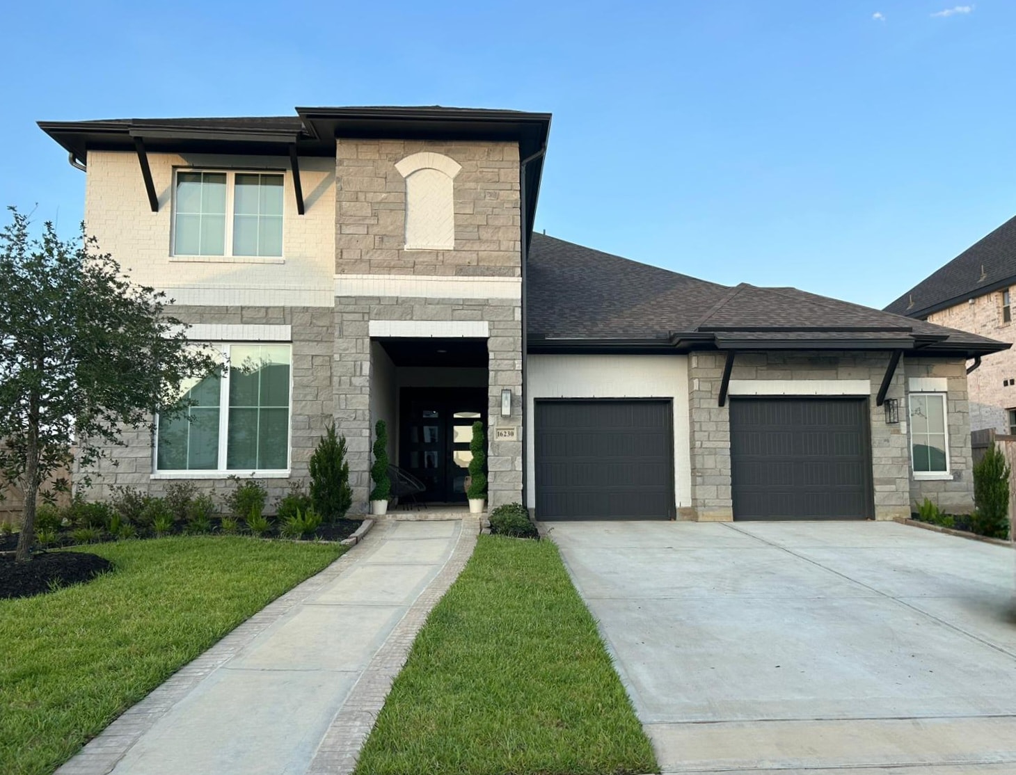 Seamless gutters on stone two-story home with triple garage — Houston TX