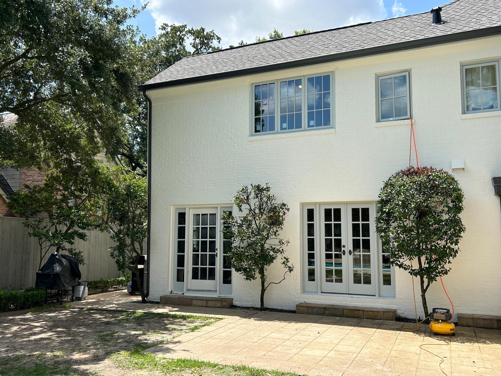 Gutter installation on white brick home with French doors and backyard — Houston TX